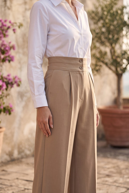 Detalle de la doble pretina abotonada del pantalón de sastrería camel
